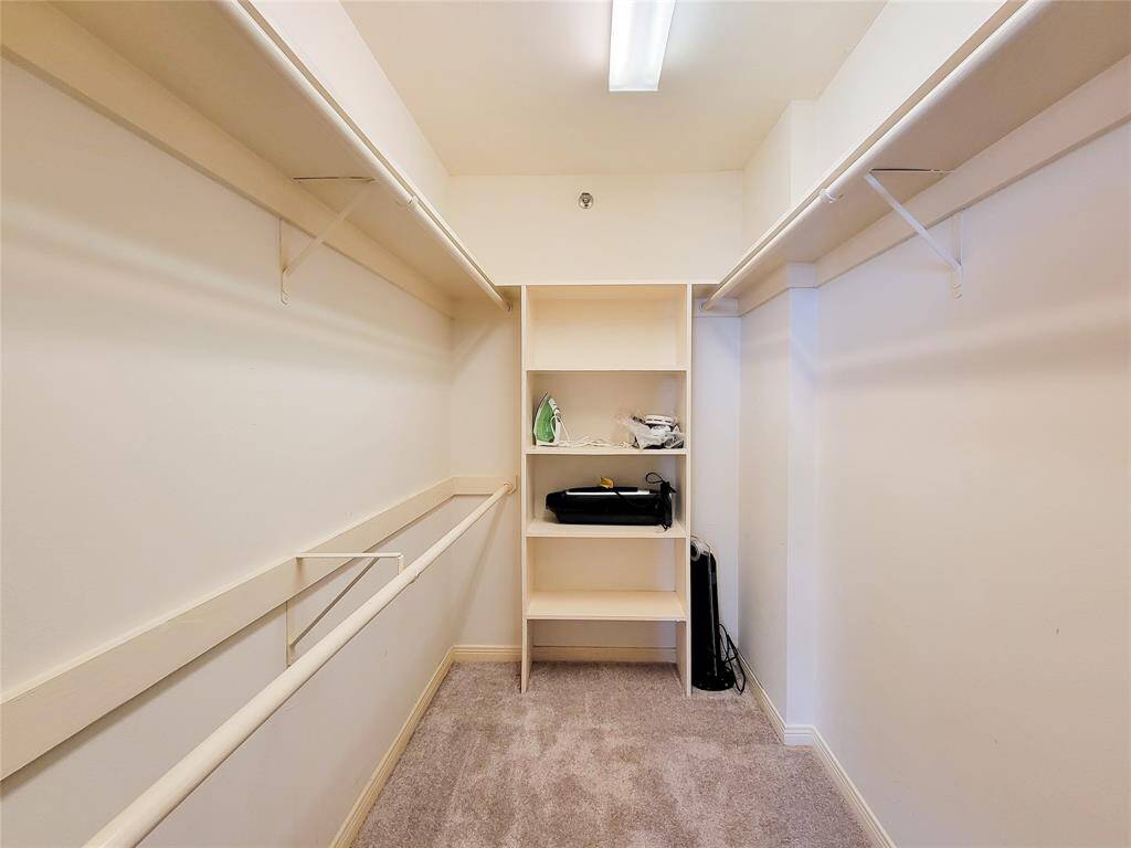 Oversized walk-in closet with carpet flooring, built-in shelves, and ample hanging space, featuring good lighting.