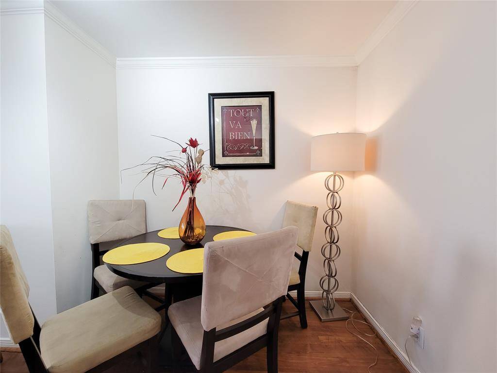 Cozy dining area with a round table set for four, featuring a modern floor lamp and tasteful wall art, complemented by neutral tones for a welcoming ambiance.