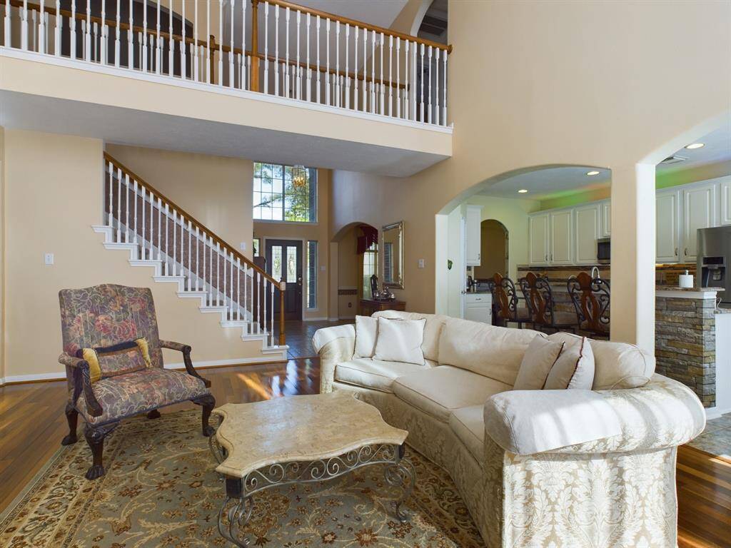 A grand staircase leads to an upper level, while the living room seamlessly connects to the kitchen with a breakfast area.