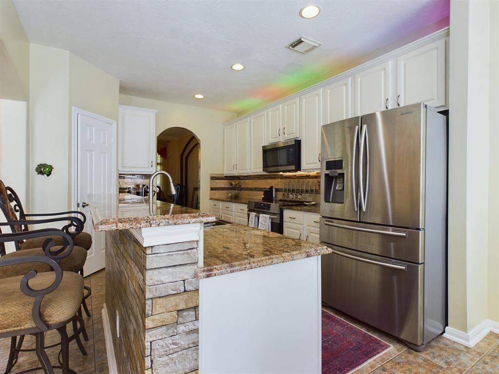 This kitchen features modern stainless steel appliances and a stylish stone accent on the island that provides extra seating