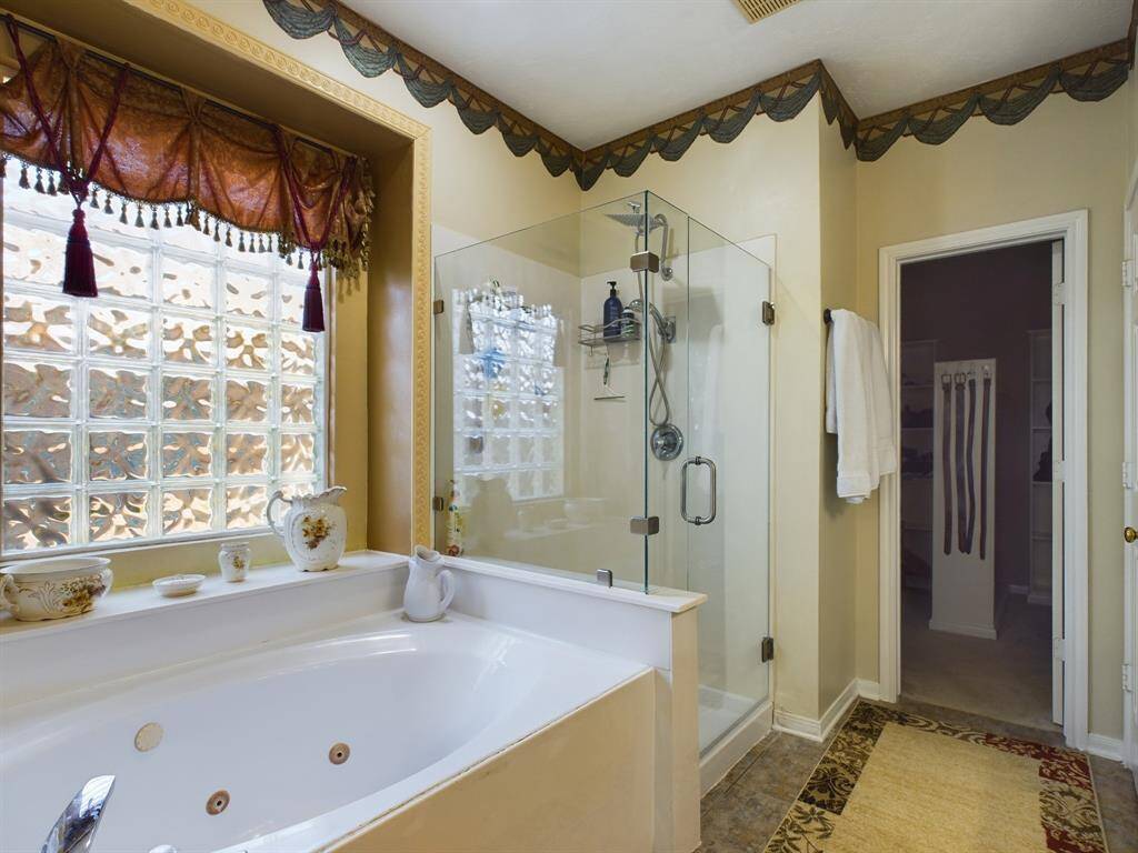 The primary bathroom features a luxurious jetted tub and a modern glass-enclosed shower.