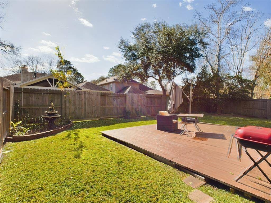 This backyard features a spacious wooden deck, perfect for relaxation or entertaining.