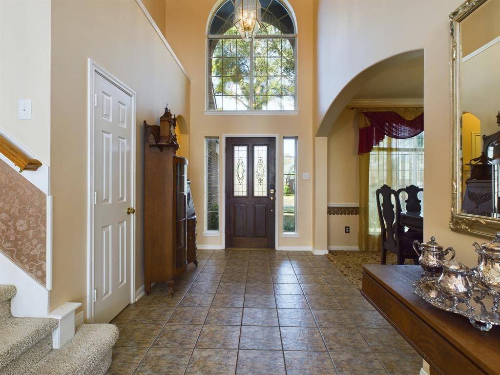 This inviting entryway features high ceilings  and a large arched window that fills the space with natural light.