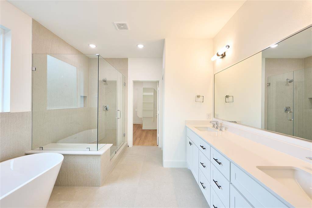 Spa-like bathroom featuring a soaking tub and dual vanities.?