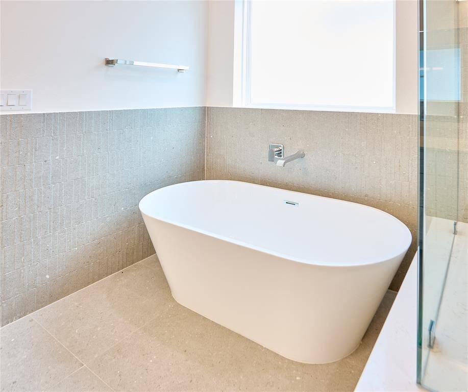 Relax and unwind in this spacious ceramic tub, complemented by sleek, modern wall tiles.