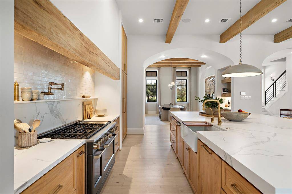 A reclaimed wood beam header and Zellige Cle tile back splash surround this 48" GE Cafe Ranch/Cooktop.