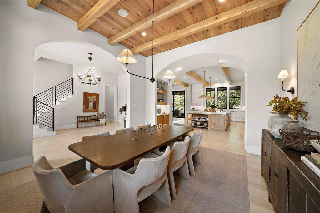 Large dining room with a warm wood ceiling, reclaimed beams, and arched entryway ways.