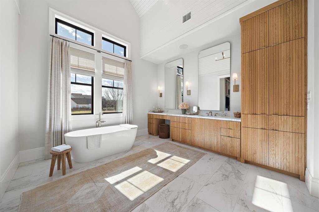 Breathtaking 1 of 2 bathrooms in the primary suite. Custom cabinets throughout with a soaking tub, sink with upgraded fixtures, and a separate vanity space.