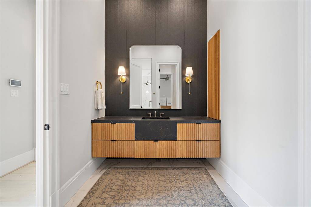 This is the 2nd bathroom in the primary suite designed with a black focal wall, wood trim cabinetry, and floating vanity.  It too has a private lavatory and dedicated entry to the walk-in shower.