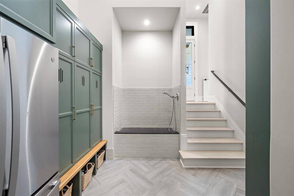Access the house from the garage through a mudroom with built-in lockers, additional refrigerator space, and a dog washing station.