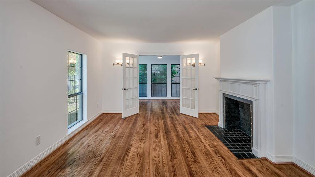 The first floor living area features tall windows, a mock fireplace and a home office made private with French doors.
