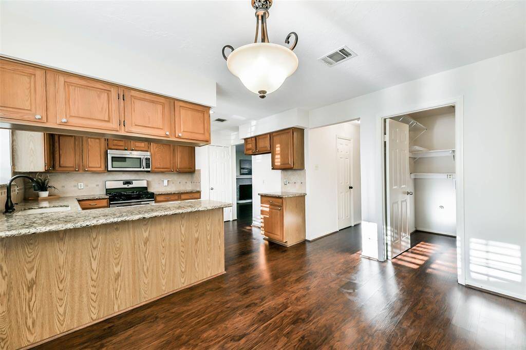Situated between the garage entrance and the kitchen, you'll find a casual breakfast area with luxury vinyl plank floors, neutral paint, a side-facing window with plantation shutters, and a granite-top breakfast bar leading into the kitchen.
