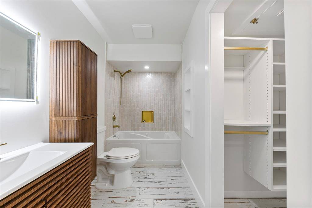 The primary bathroom features modern upgrades, including a backlit mirror and a sleek tub/shower combo for both comfort and style
