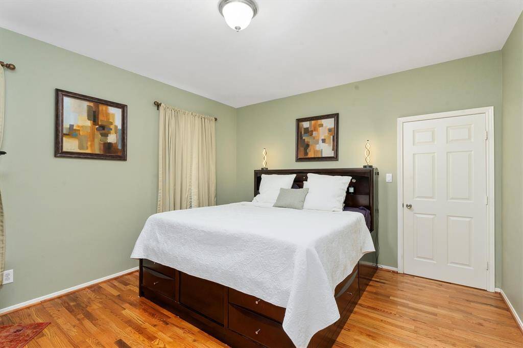 The primary bedroom is located on the 1st floor and features a cozy atmosphere with soft green walls & hardwood flooring.