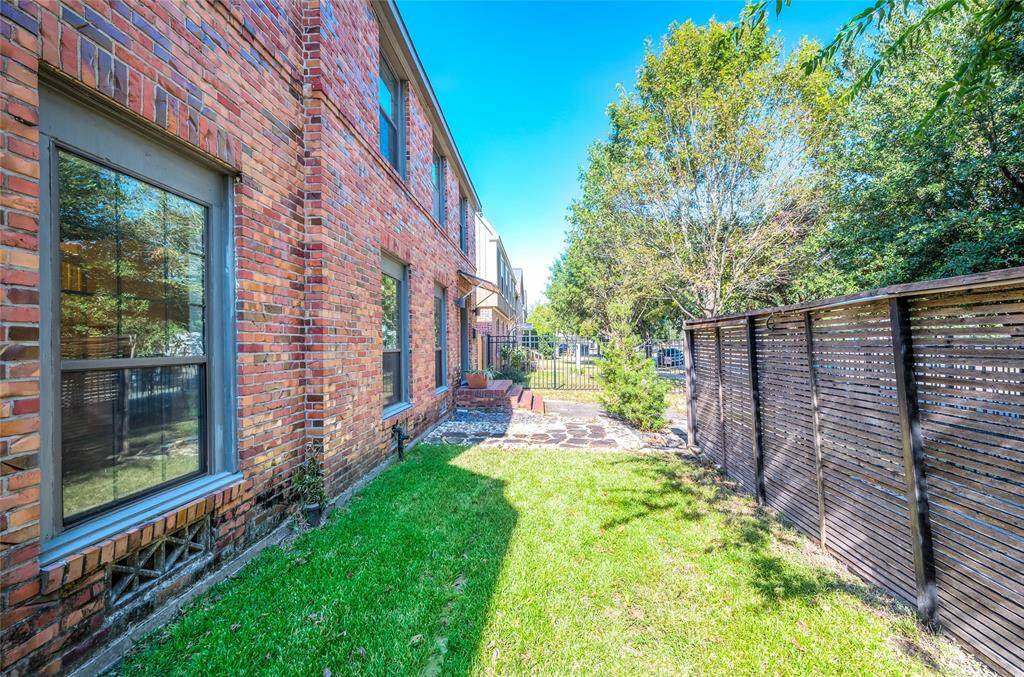 The fully fenced front yard with privacy screen to the right and patio by the front porch.
