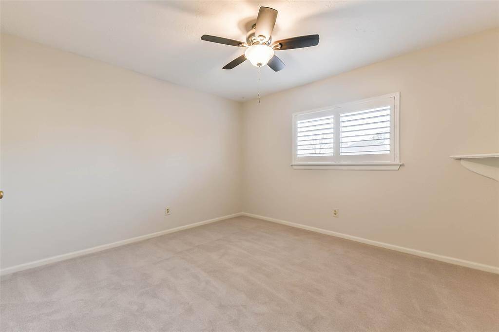 In another secondary bedroom, find a contemporary lighted ceiling fan, plush new carpet, a window with plantation shutters, and a roomy walk-in closet.