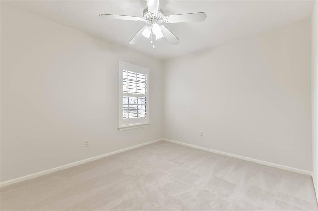 The fourth and final bedroom in the home is similar to the others, also boasting neutral paint, plush new carpet underfoot, a lighted ceiling fan, a window with plantation shutters, and a generous walk-in closet.