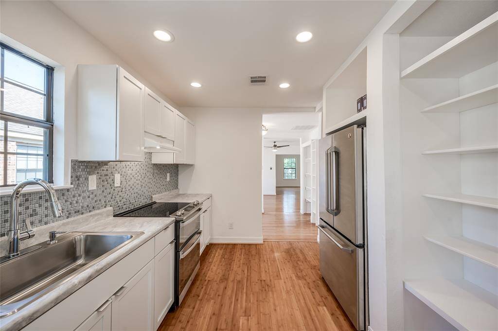 Recessed lighting, beautiful wood floors. Plenty of pantry space to the right and beyond the kitchen in the breakfast room. Back stairs lead to the back yard.