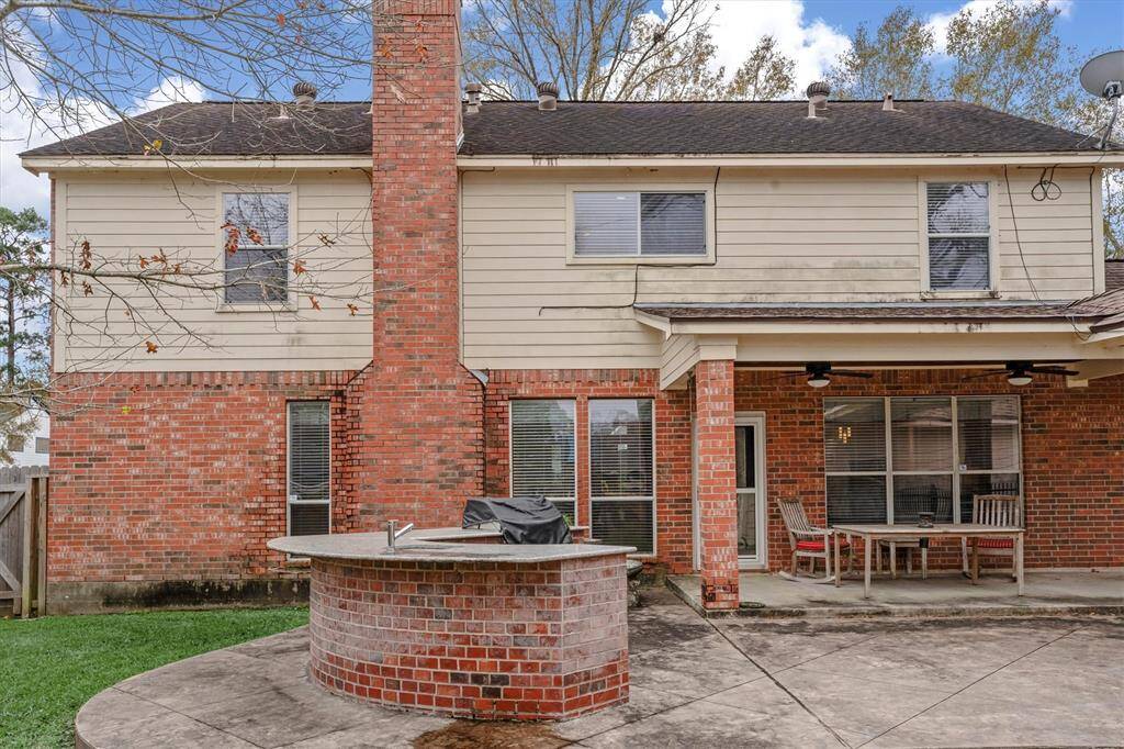 Wonderful covered patio and outdoor kitchen are perfect for entertaining. The area is paved and partially grassy, offering a versatile outdoor space.