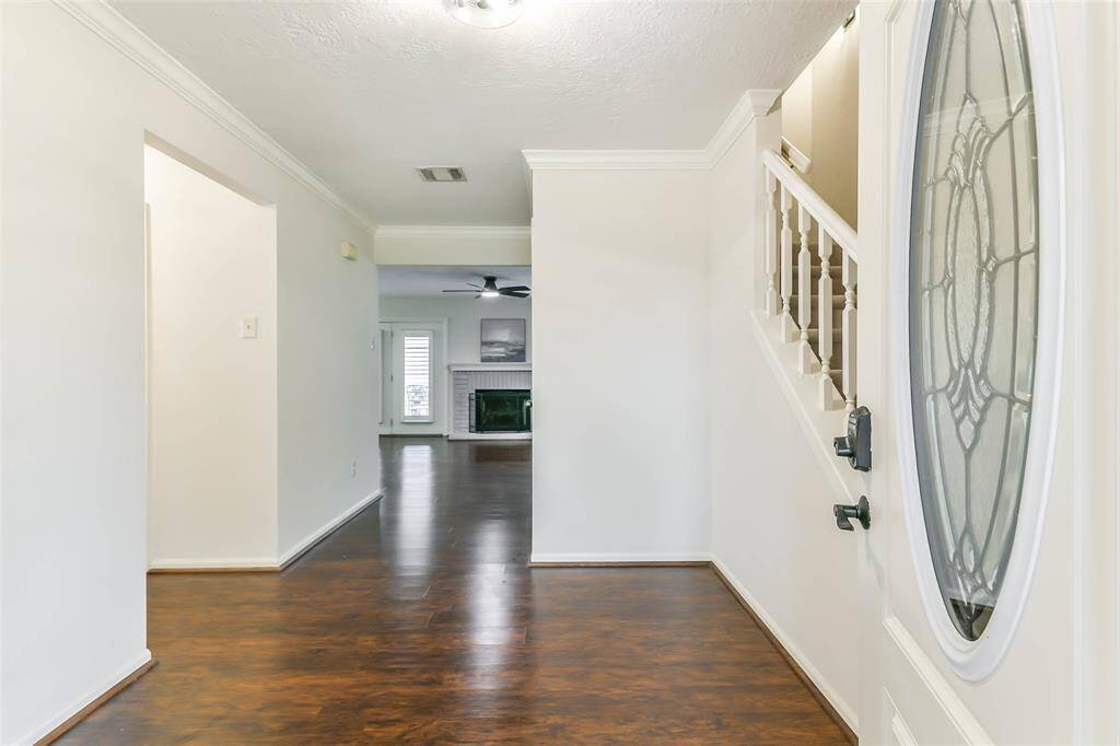 The covered front porch makes way to a door with an oval-shaped leaded glass insert and an inviting foyer that features luxury vinyl plank floors, neutral paint, crown molding, and a convenient half bathroom beneath the staircase.