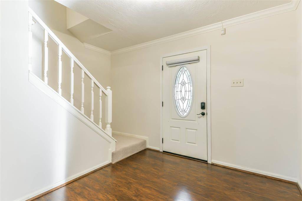 The covered front porch makes way to a door with an oval-shaped leaded glass insert and an inviting foyer that features luxury vinyl plank floors, neutral paint, crown molding, and a convenient half bathroom beneath the staircase.