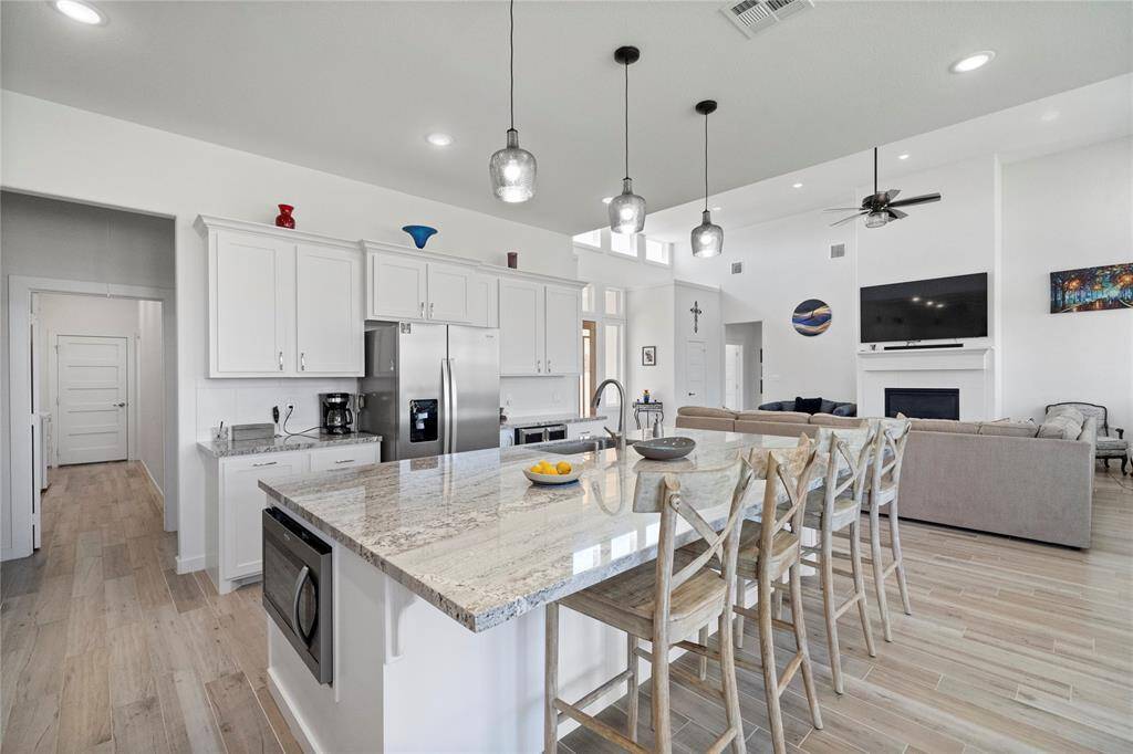 Beautiful open kitchen has lots of custom cabinets, granite counters, plus a large center island with a breakfast bar.