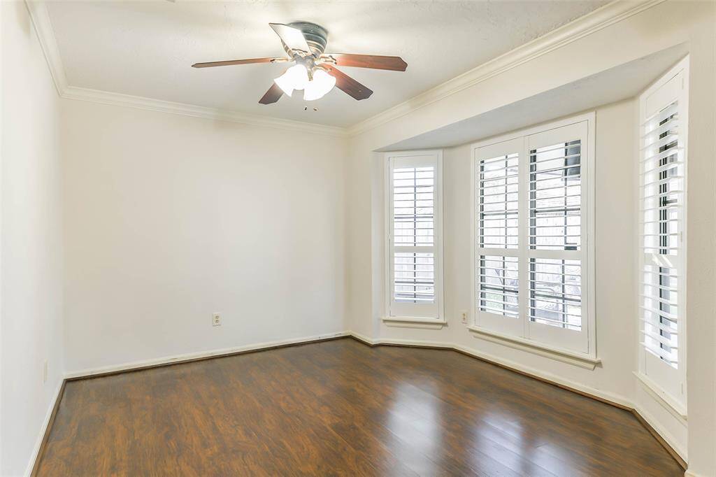 Perfect for use as a dining area or a home office, this sunlit space adjacent to the family room and kitchen offers a lighted ceiling fan, neutral paint trimmed with crown molding, luxury vinyl plank floors, and rear-facing bay windows dressed with plantation shutters.