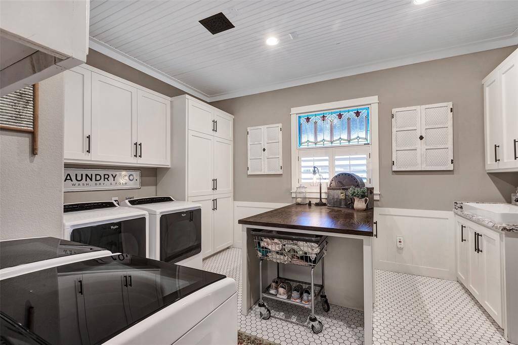 Delightful oversized laundry room has 2 separate washer/dryer hookups, loads of cabinet style storage, island workspace and laundry sink