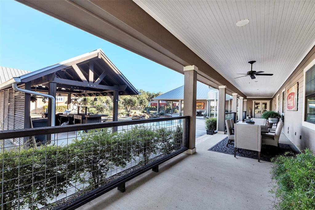 The covered porch extends around the entire back of the house surrounding the pool, with wood ceiling details, recessed lighting, ceiling fans and custom fence railing to add to the charm
