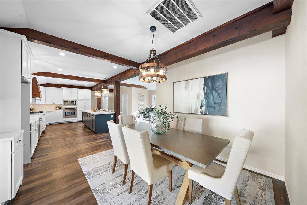 The dining area is located between the kitchen and the living room and features wood beams and a chandelier.