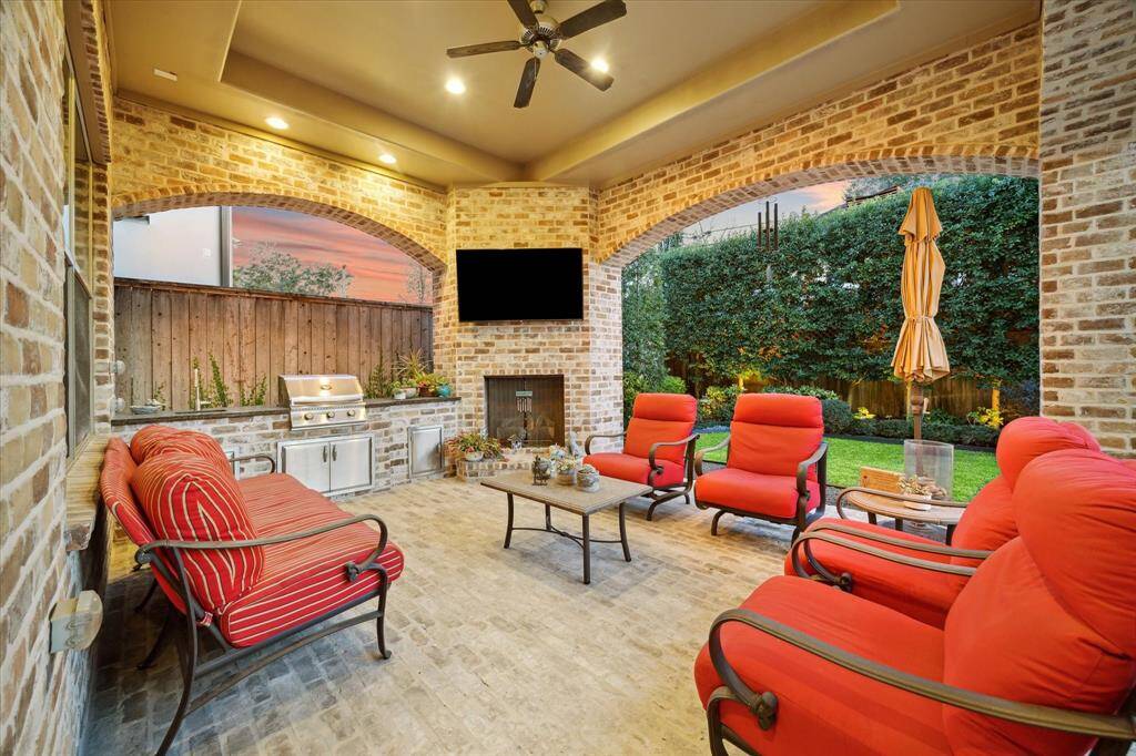 The outdoor space is an entertainer's dream, featuring a covered patio, an outdoor kitchen with a built-in grill, a fireplace, and a beautifully landscaped garden. The area is perfect for hosting gatherings or enjoying a quiet evening under the stars.
