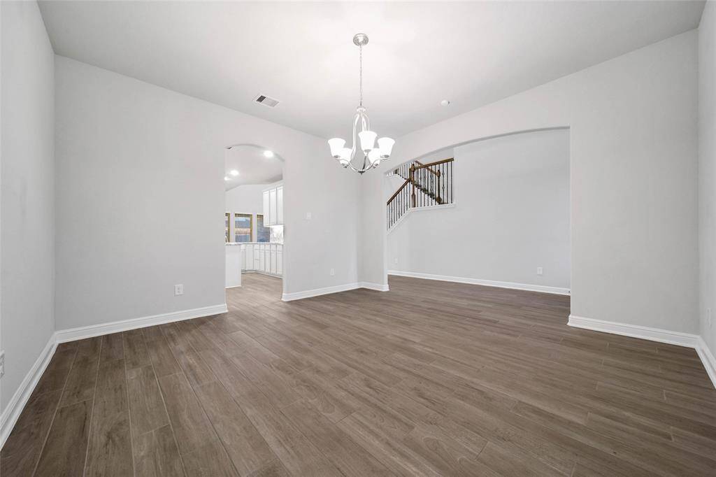 This is a bright and spacious home office with large windows and features contemporary wood look tile flooring and a neutral color palette.
