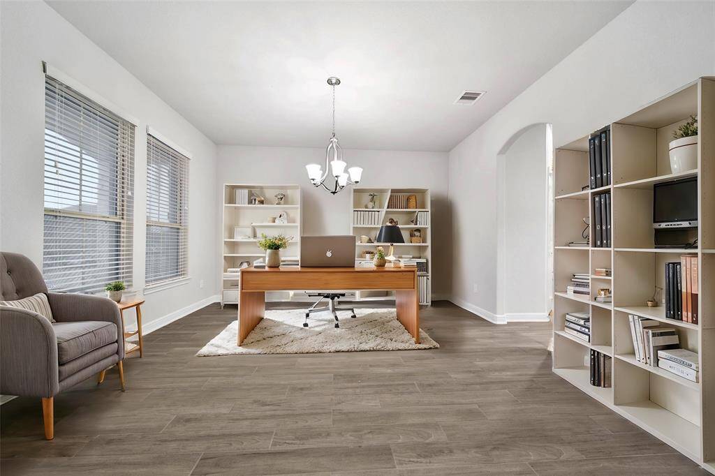 This is a bright and spacious home office with large windows and features contemporary wood look tile flooring and a neutral color palette.