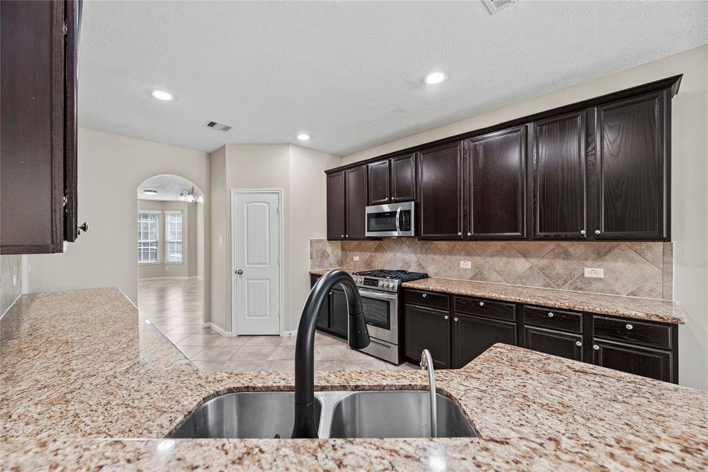Granite countertops paired with a coordinating stone backsplash not only provide a durable and elegant surface for food preparation but also add a touch of luxury and sophistication to the kitchen.