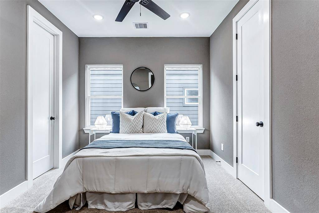 Bright and airy second bedroom with two windows and a ceiling fan.