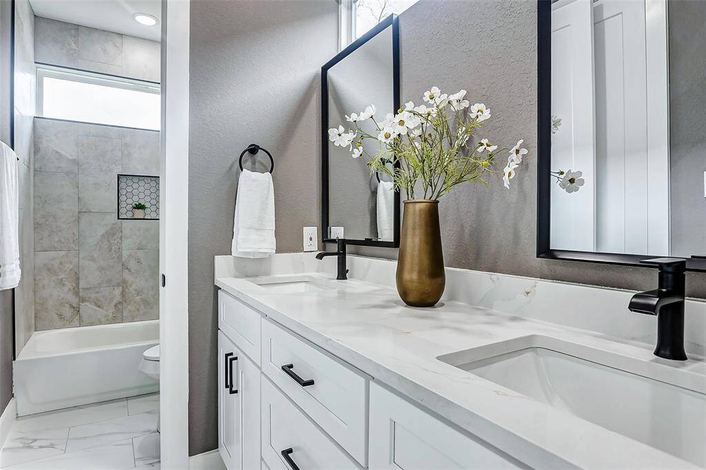 Elegant Jack and Jill bathroom featuring sleek white cabinetry and stunning quartz countertops.