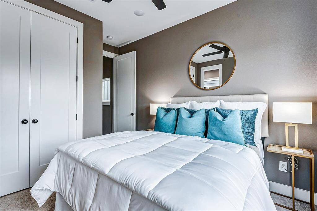 Third bedroom featuring soft neutral tones, a stylish round mirror, and ample natural light.