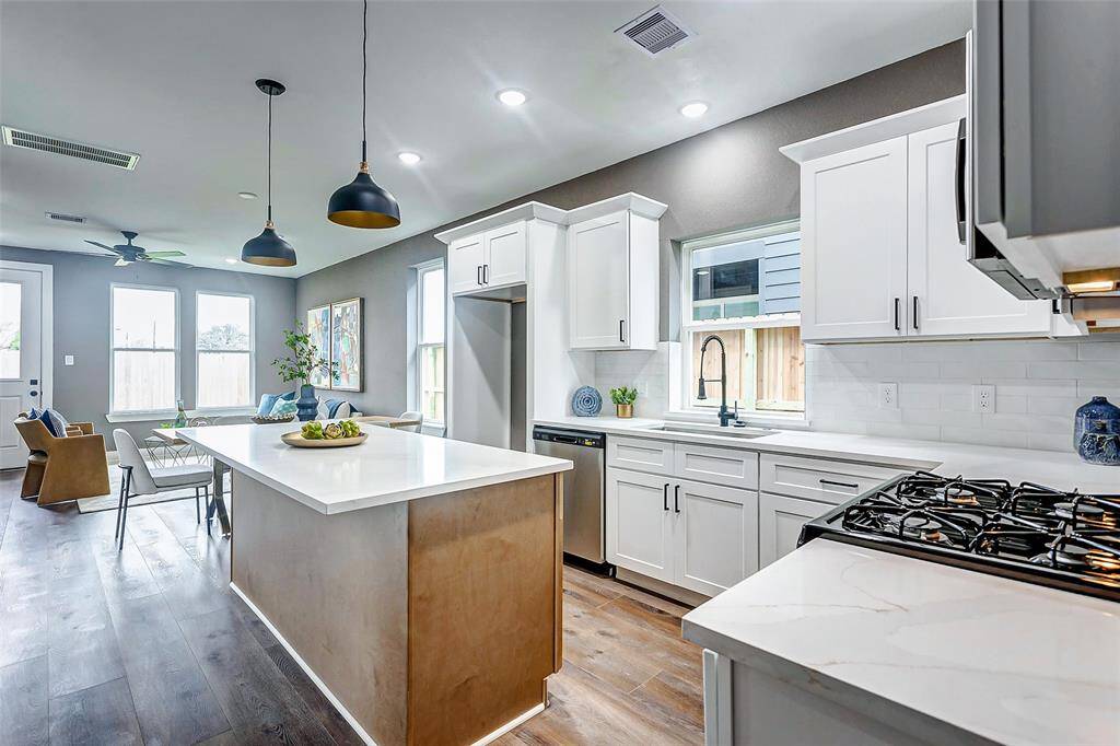 Sleek white cabinetry, a quartz island, and open layout make this kitchen perfect for cooking and entertaining.