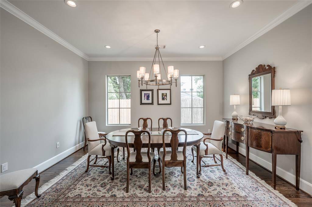 Light-filled formal dining room features windows overlooking the backyard, recessed lighting, chandelier, crown moulding, and hardwood floors.