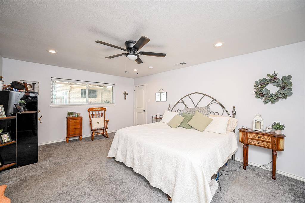Virtually Staged: Unwind after a long day in this spacious Primary Bedroom! Featuring carpet floors, recessed lighting, and a ceiling fan.