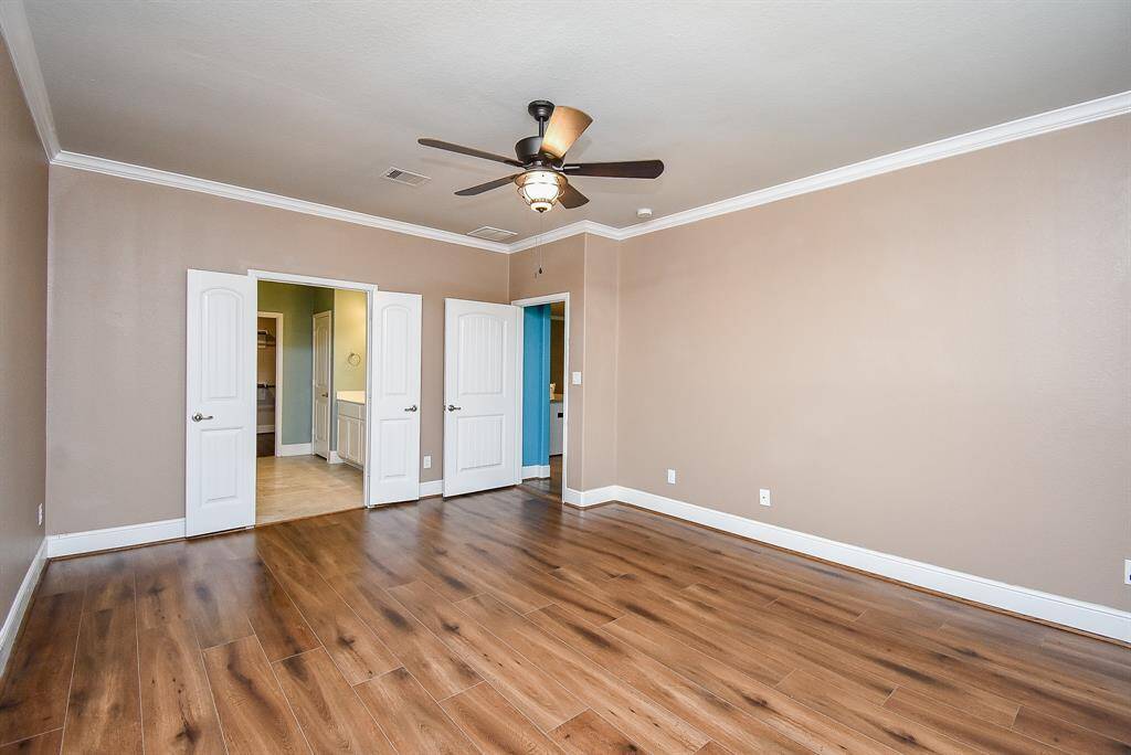 Elegant primary suite boasting refined crown molding, sophisticated custom trim, and stylish plantation shutters.