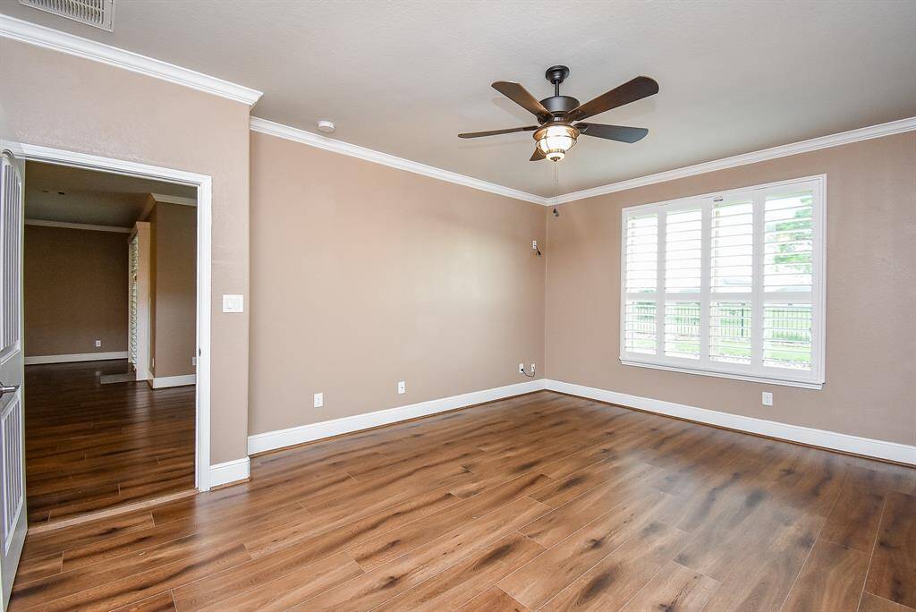 Elegant primary suite featuring sophisticated crown molding, bespoke trim, and stylish plantation shutters. Perfect views of the pool and lake!