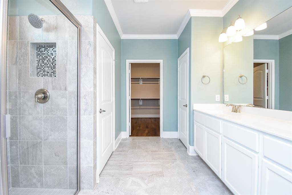 Primary bath features a large roll-in glass shower with a bench and dual under mounted sinks