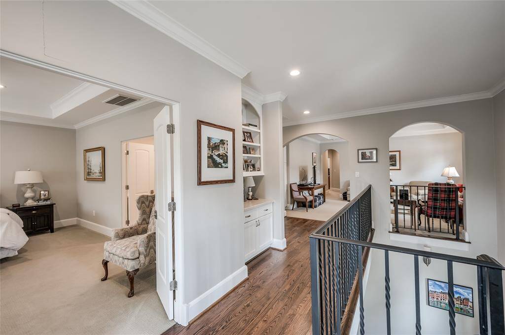 Second floor landing with hardwood floors, built-in shelves, and arched openings to game room/upstairs den