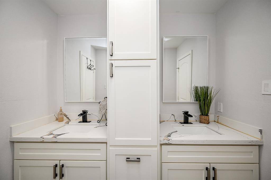 Secondary bedroom with white cabinetry, double sinks, and quartz countertops.