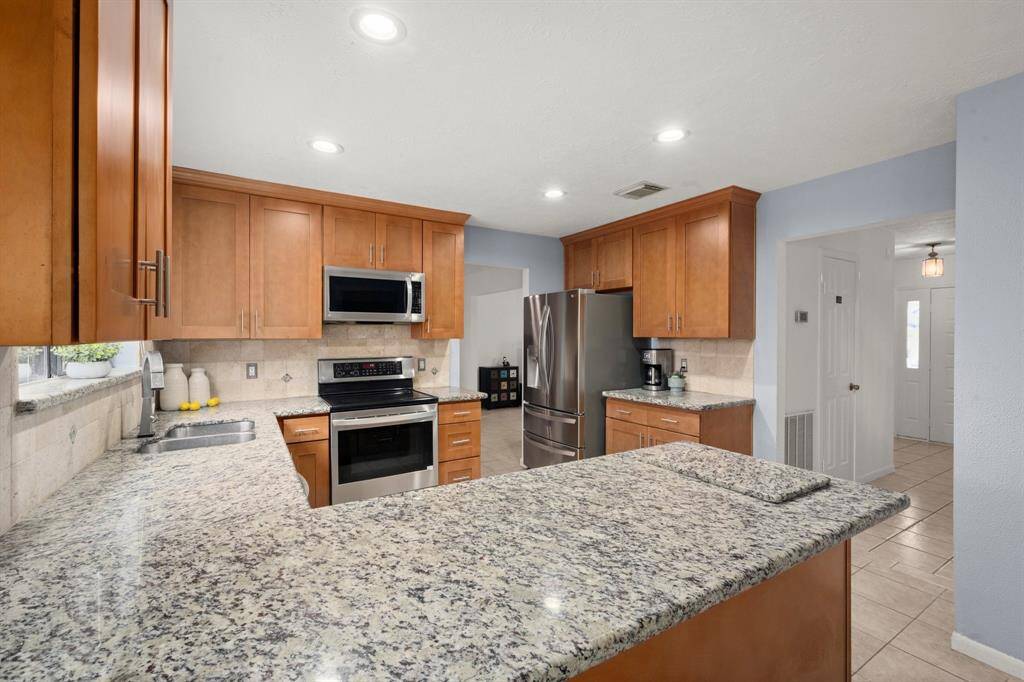 This granite countertop is not only beautiful but timeless.  This view shows the large range and overmounted stainless steel microwave and vented fan.  It is easy to access the dining room and the front foyer to greet your holiday guests.