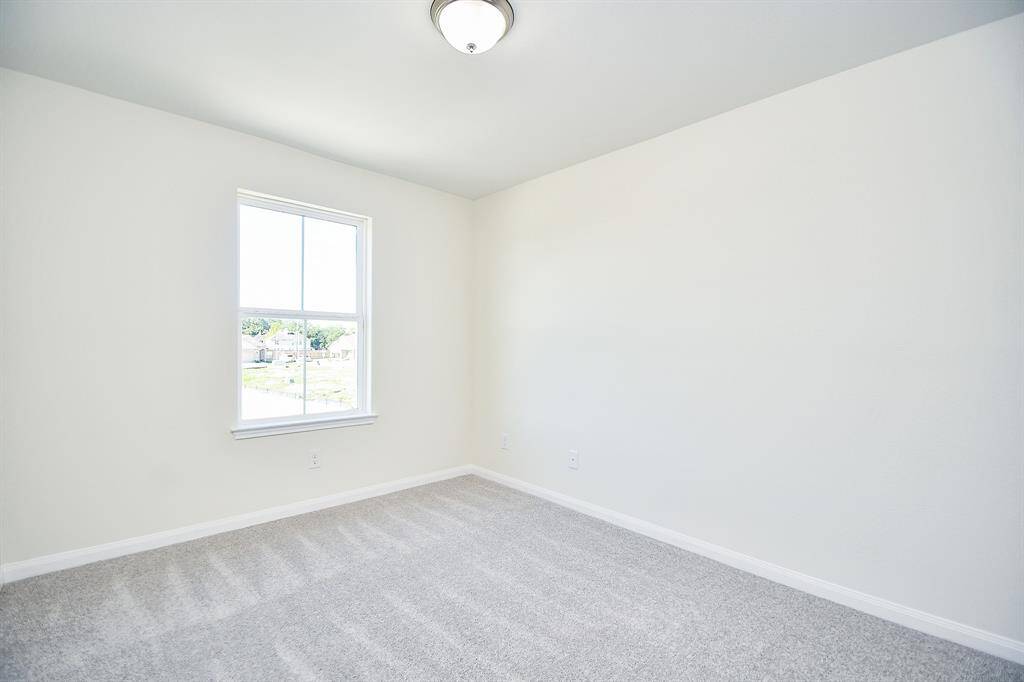 Empty room with gray carpet, white walls, a single window, and a flush mount ceiling light fixture.