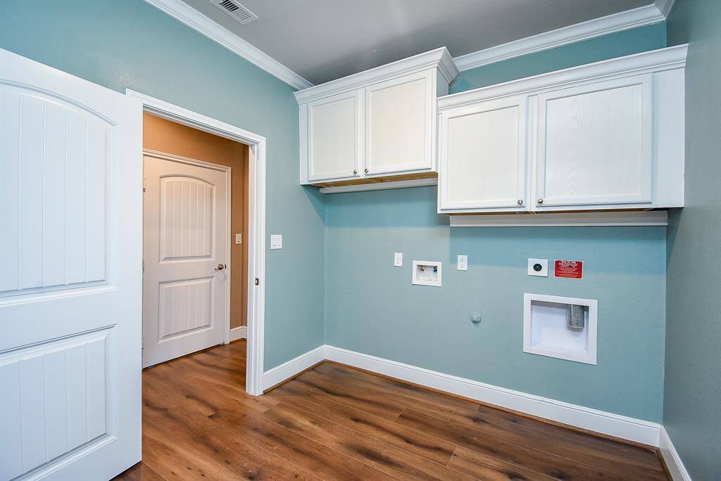 Experience seamless functionality with dual access to the laundry room from both the hallway and the primary suite, complemented by custom trim, sophisticated crown molding, and ample cabinetry for smart storage solutions.