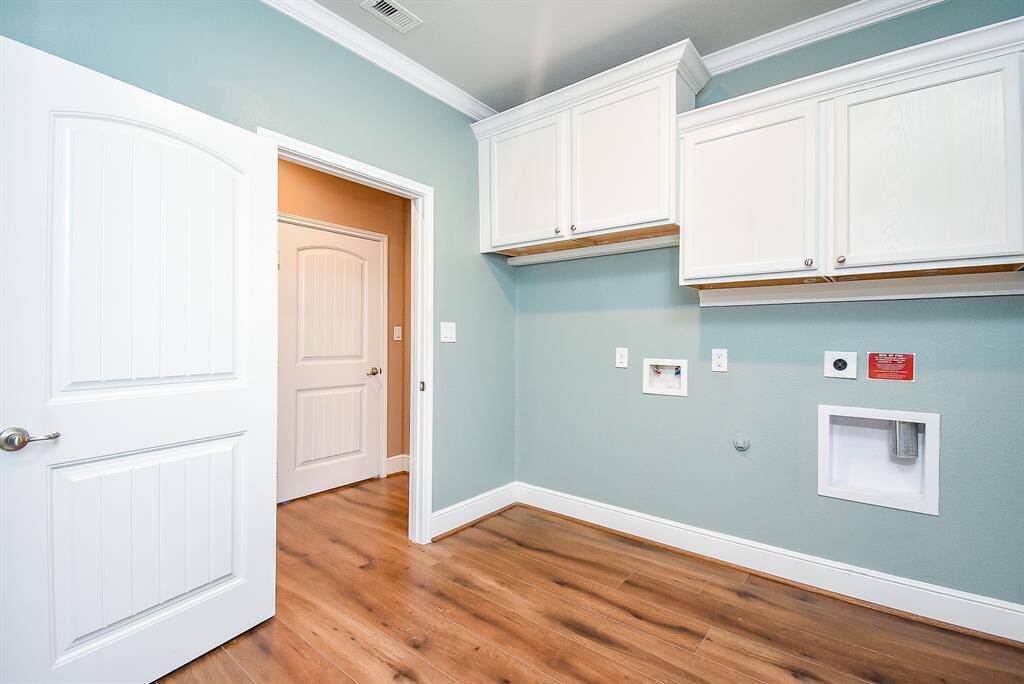 Laundry room can be accessed from the hall and the primary closet. It also has custom trim, crown molding and cabinets for storage.