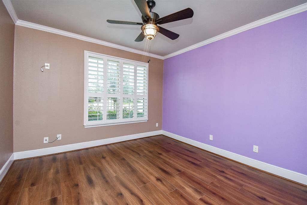 Charming secondary bedroom located in the front features elegant crown molding, custom trim, plantation shutters, and durable luxury vinyl plank flooring.